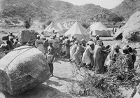 view M0001537: Photograph of the local workforce hauling on rope to move boulders at Jebel Moya, Henry Wellcome's archeological excavation site in Sudan, with tents in the background