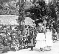 view M0002729: Two African men, possibly practioners of traditional medicine, standing in front of a group of people