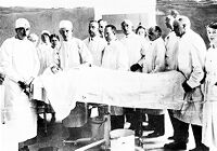 view M0010060: Sir Harold Gillies standing at the head of an operating table with his hospital staff