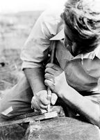 view M0015962: Leon Coutier making flint implement using technique of pressure-trimming from the shoulder