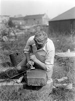 view M0015965: Leon Coutier making flint arrowhead using technique of pressure-trimming from the shoulder
