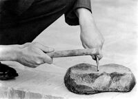 view M0015958: A.D. Lacaille making a prehistoric-style graver (burin) using Coutier's side-blow method: blow about to fall