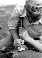 view M0015963: Leon Coutier making flint arrowhead using technique of pressure-trimming from the shoulder